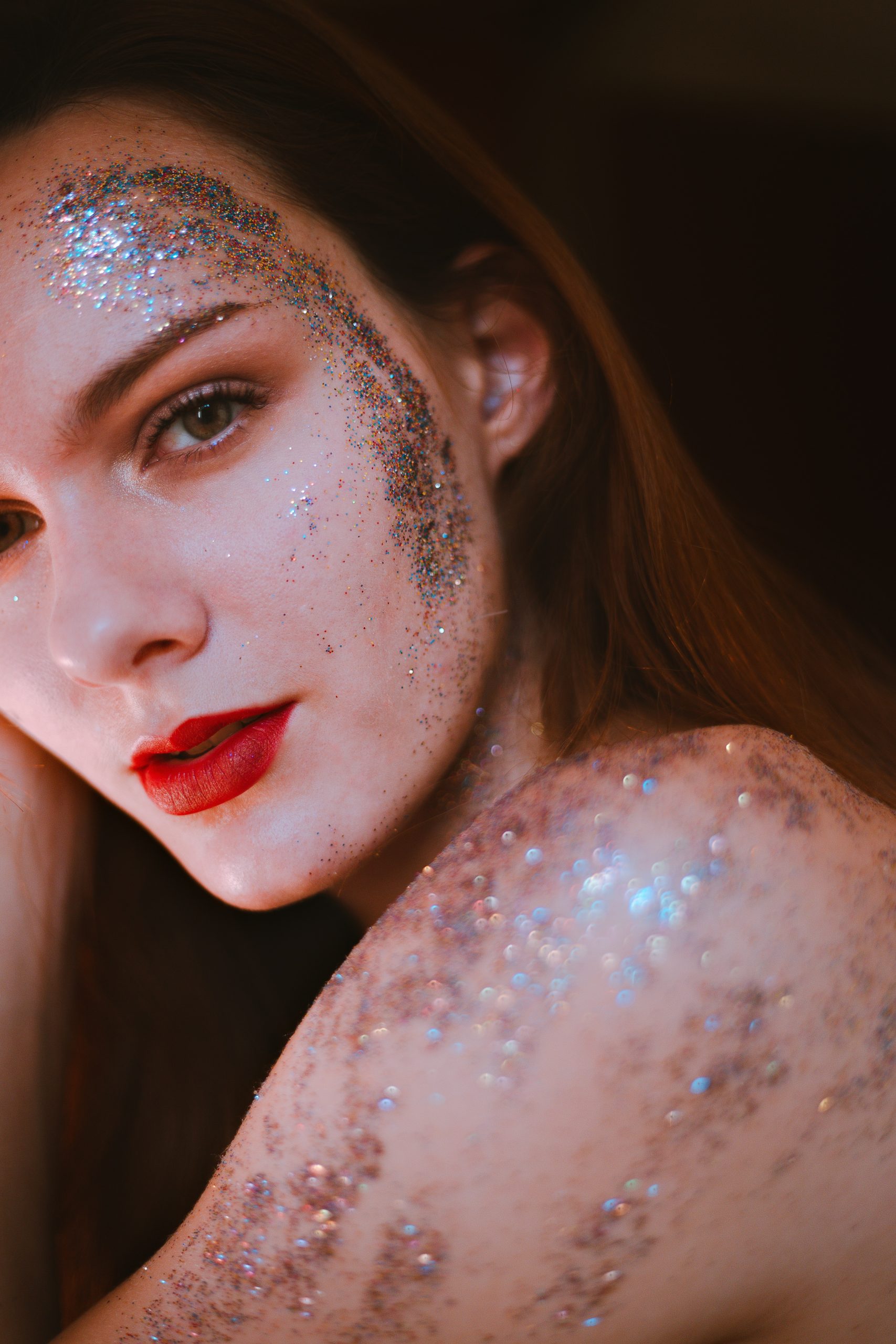 woman wearing sparkly makeup and red lipstick, editorial makeup look